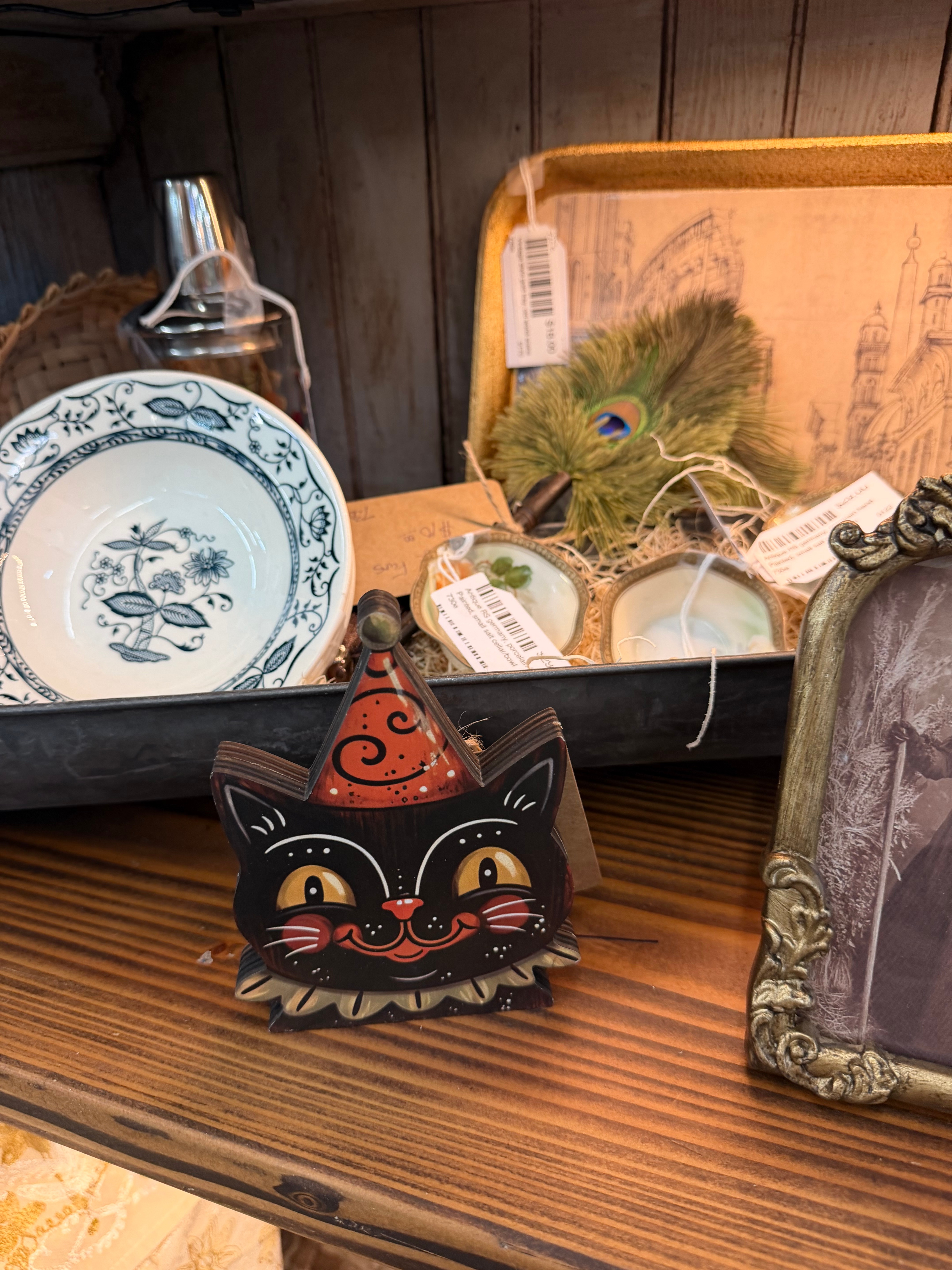 A hand-painted wooden black cat head wearing a party hat, in vintage Halloween folk-art style